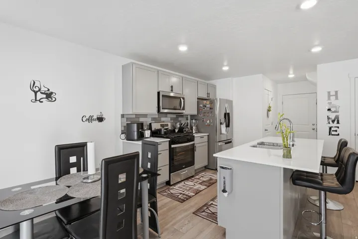 Modern kitchen featuring stainless steel appliances, including a built-in microwave and range, paired with gray cabinetry and white quartz countertops