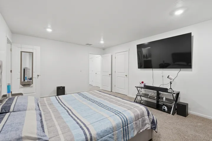 Carpeted bedroom featuring white walls, recessed lighting, and white paneled doors