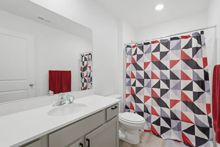 Bathroom featuring a single vanity with a white countertop, an undermount sink, and light gray cabinetry with black hardware