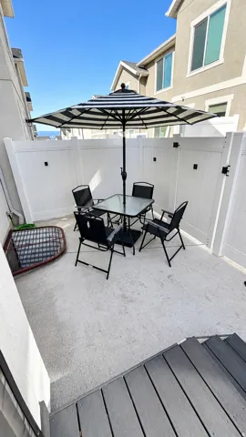 Private concrete patio area enclosed by white privacy fencing, featuring composite decking stairs