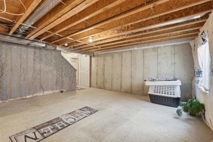 Unfinished basement with exposed ceiling joists and concrete flooring