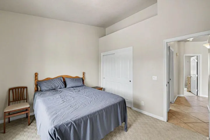 Bedroom featuring vaulted ceilings, carpet flooring, and a sliding door closet