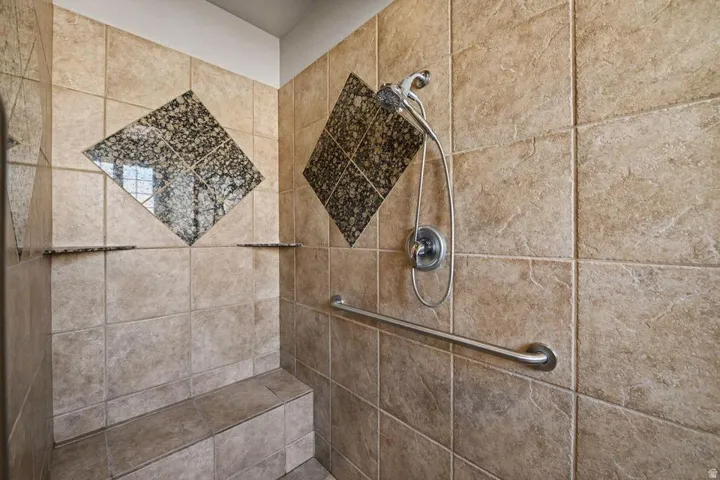 Tiled shower with decorative stone accents and integrated shelving
