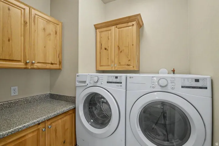 Laundry area featuring wood-finish cabinetry, a speckled countertop, and overhead storage