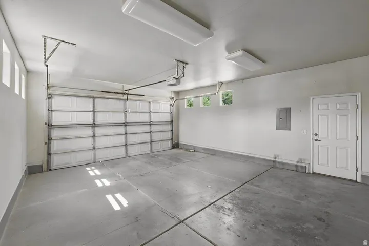 Spacious two-car garage featuring a sectional garage door, concrete flooring, and multiple ceiling-mounted light fixtures
