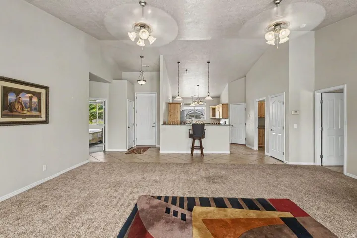 Vaulted ceilings with ceiling fans and recessed lighting illuminate an open-concept living space