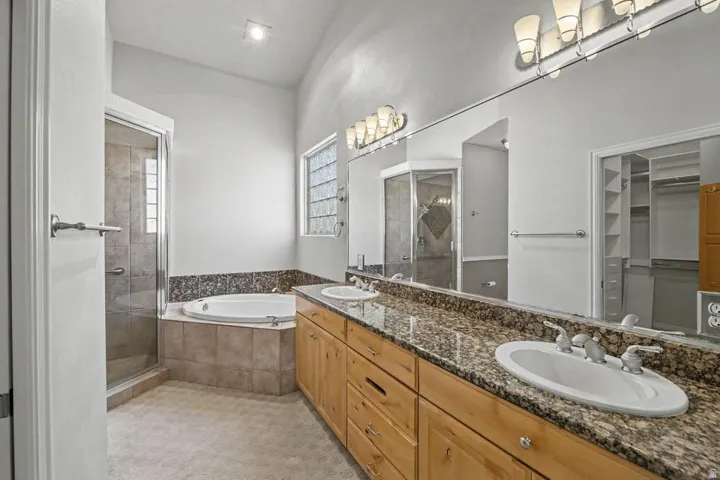 Spacious bathroom featuring a dual vanity with granite countertop, wood cabinetry, and two undermount sinks