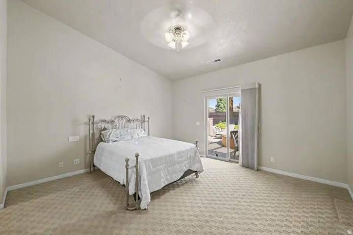 Carpeted interior space with a ceiling fan and direct access to an outdoor patio via sliding glass doors