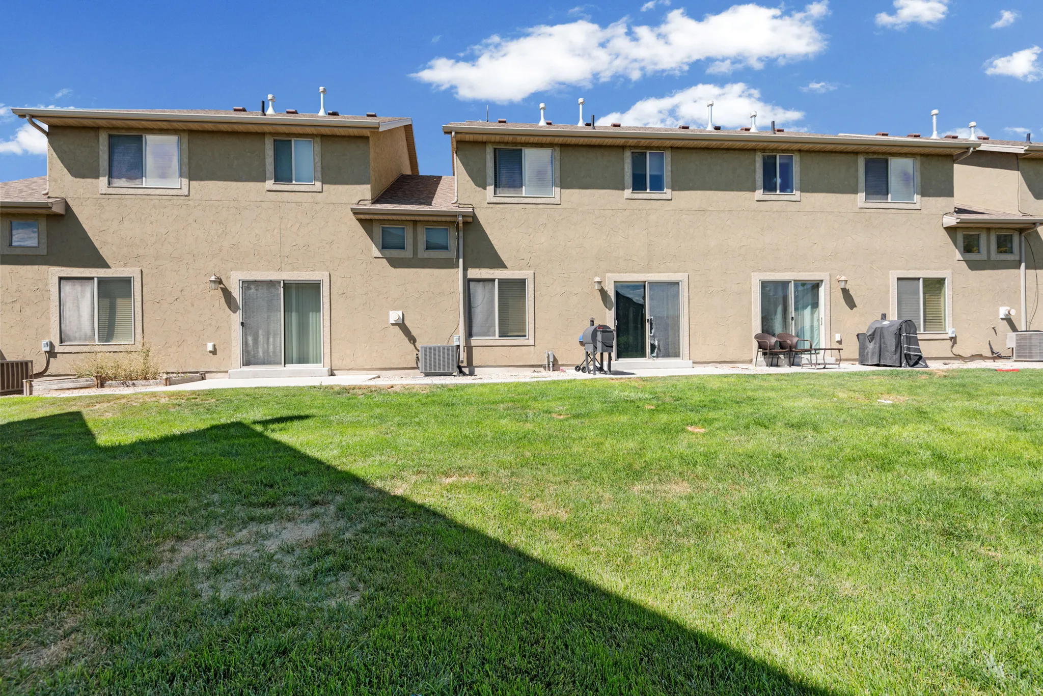 Expansive green lawn extending to multiple patio areas
