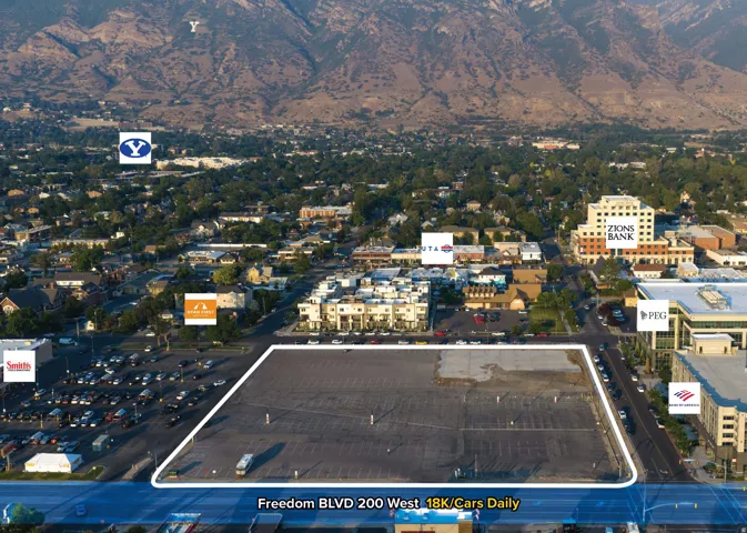 Expansive undeveloped lot featuring paved surface and surrounding commercial structures