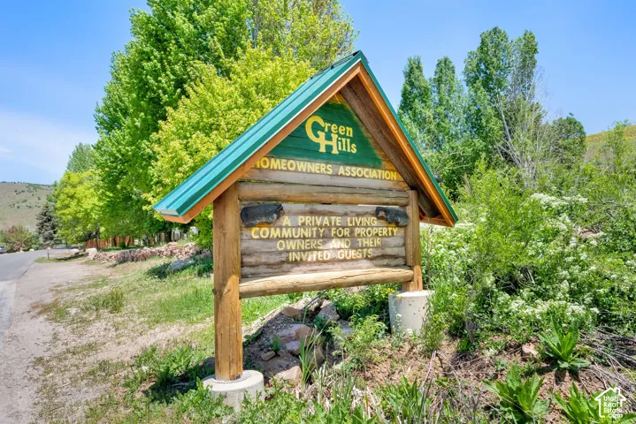 Wooden community entrance sign with a peaked green metal roof