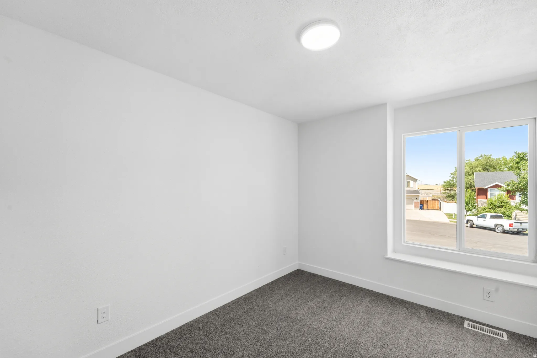 Room featuring neutral wall finishes, grey textured carpeting, and a large window with white trim