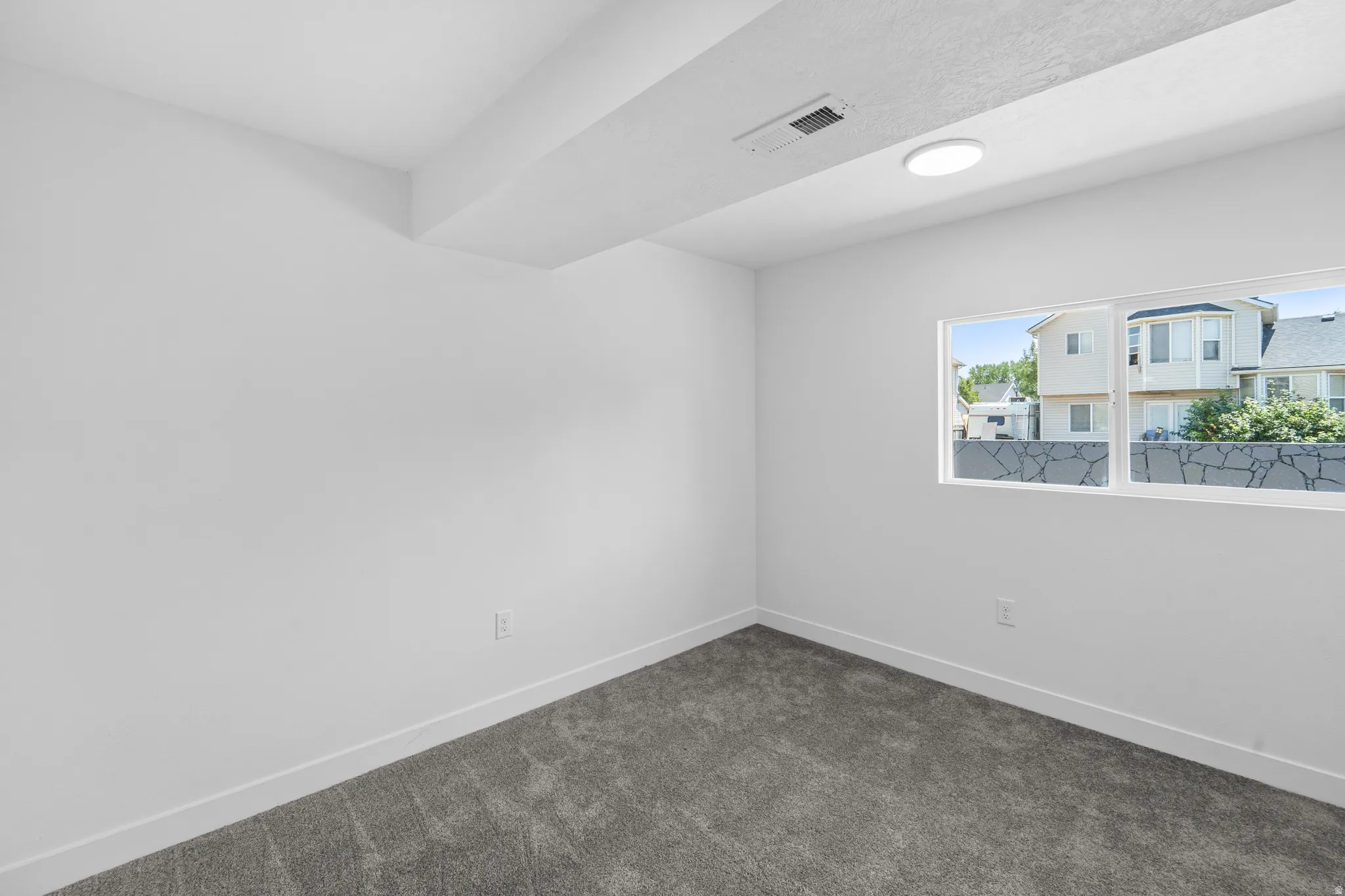 Room featuring neutral wall paint, gray carpet flooring, a single window, and flush-mount ceiling lighting