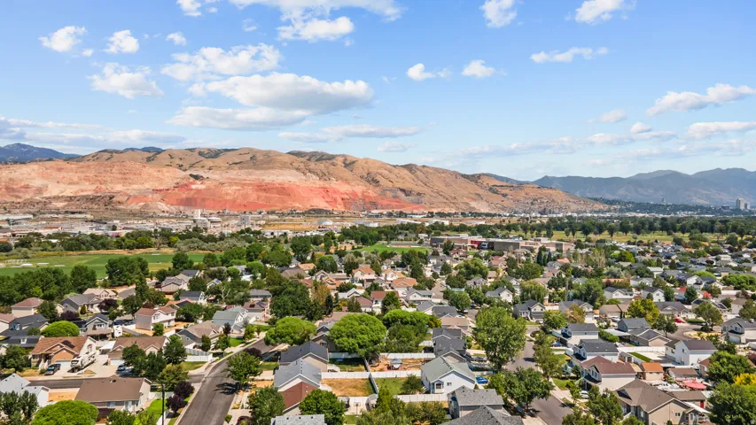 Residential neighborhood featuring diverse architectural styles, mature trees, and a mountainous backdrop