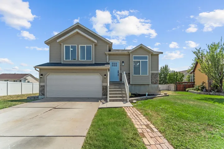 Two-story residence featuring light beige siding, stone accents, and a light blue front door