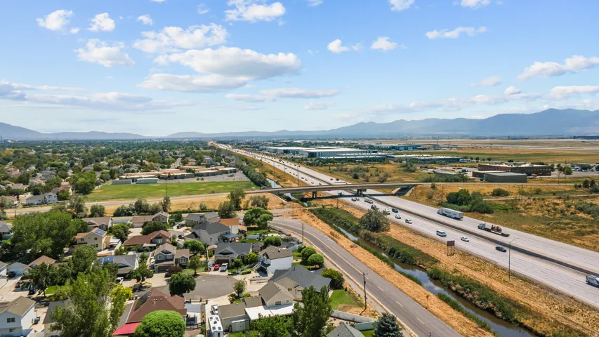 Aerial perspective showcasing a residential neighborhood alongside a multi-lane highway, with mountains in the background