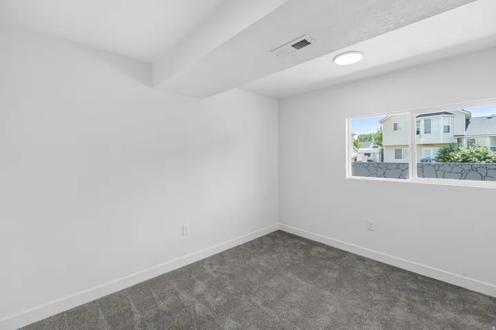 Room featuring neutral wall paint, gray carpet flooring, a single window, and flush-mount ceiling lighting
