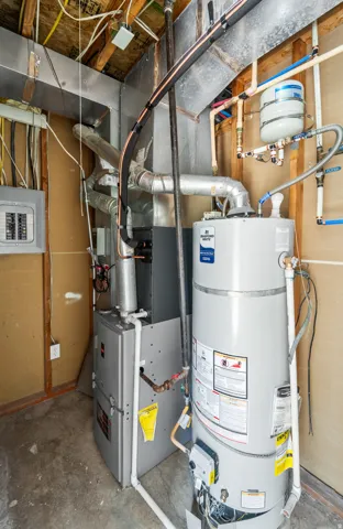 Utility area featuring a water heater, furnace, electrical panel, and exposed piping