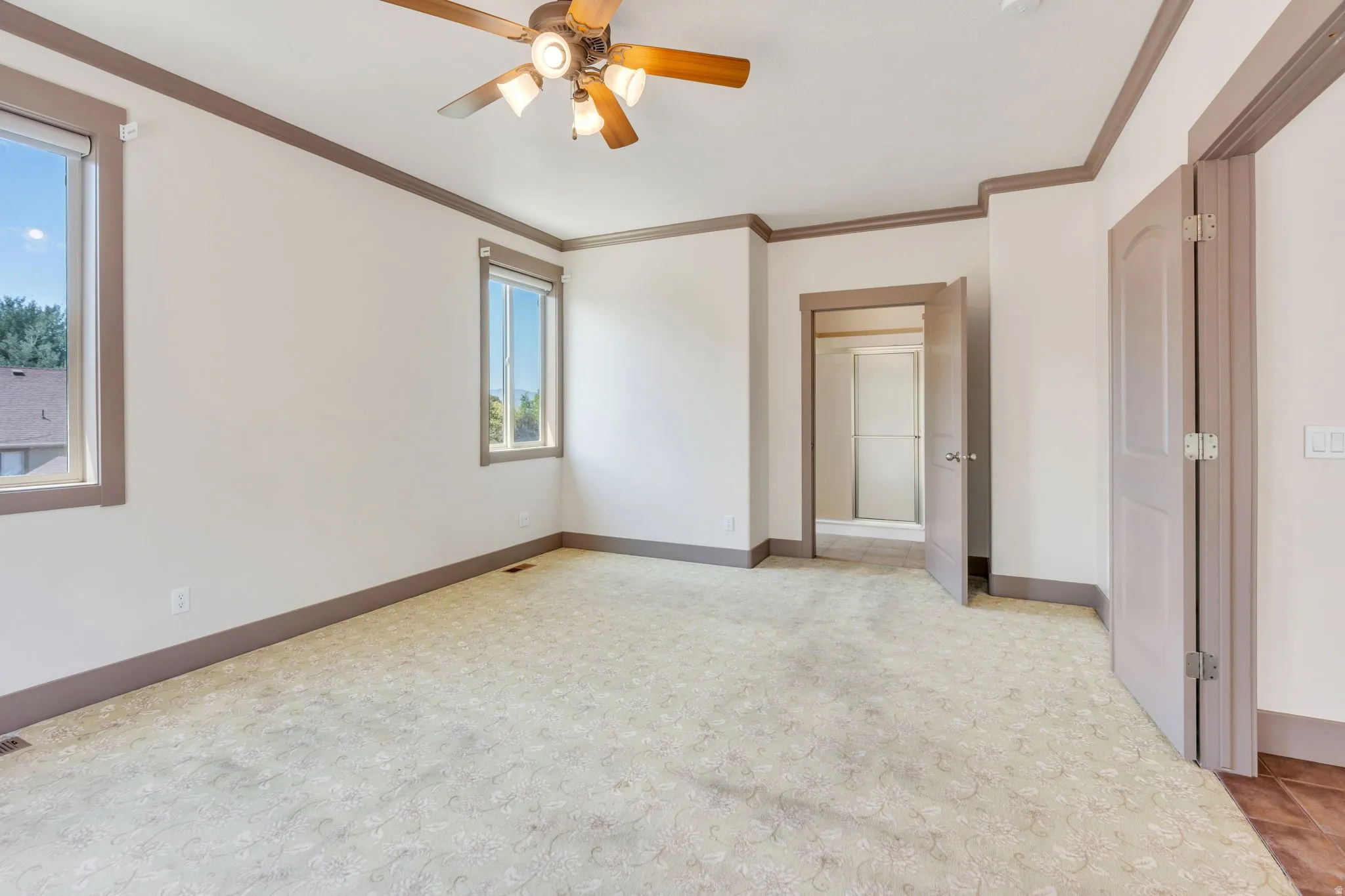 Spacious room featuring patterned carpet, a ceiling fan with integrated lighting, and two windows