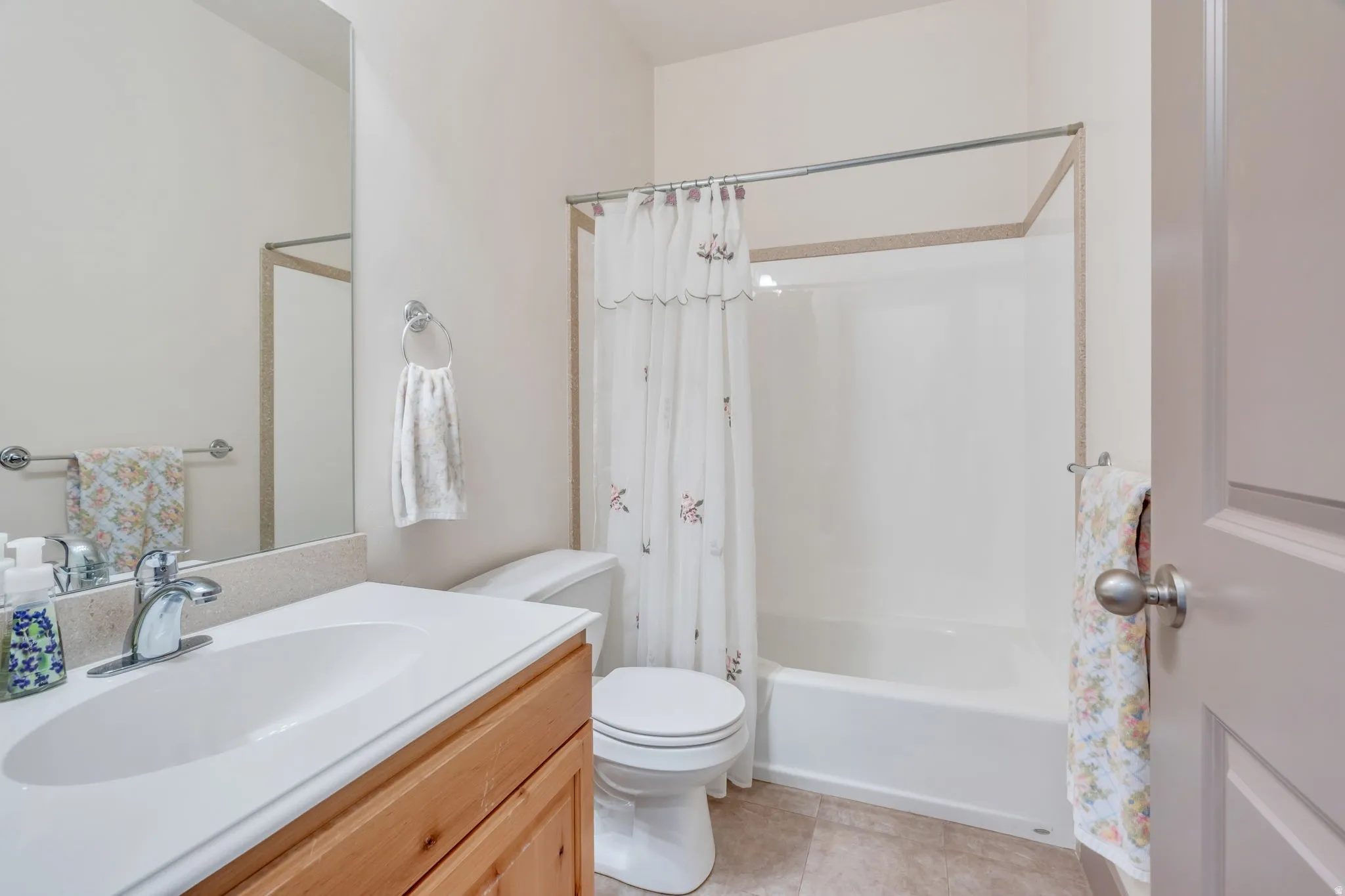 Full bathroom featuring a single vanity with wood-finish cabinetry, a light-toned countertop, and an integrated sink basin