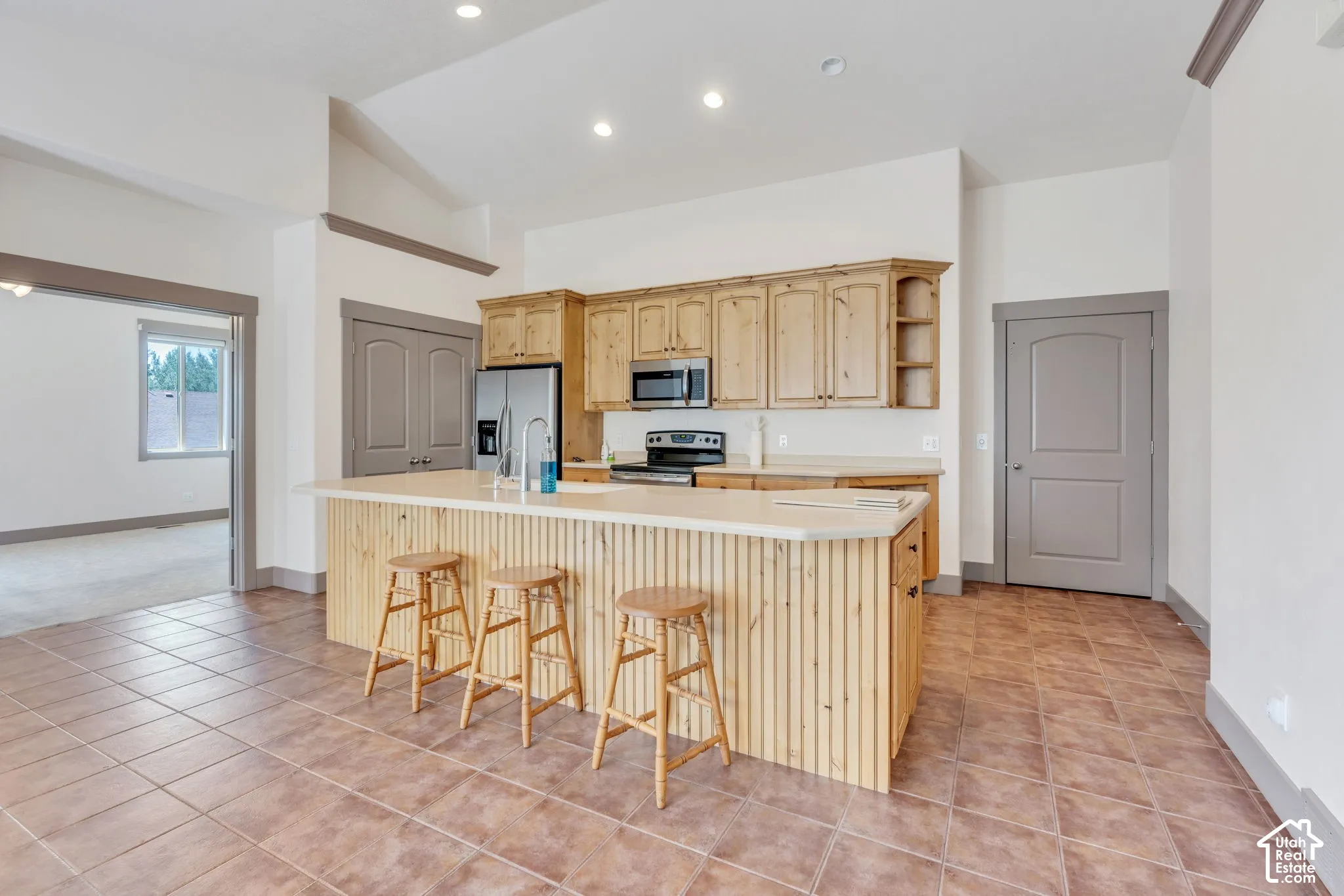 Kitchen featuring a central island with paneling, light-toned cabinetry, stainless steel appliances, and recessed lighting