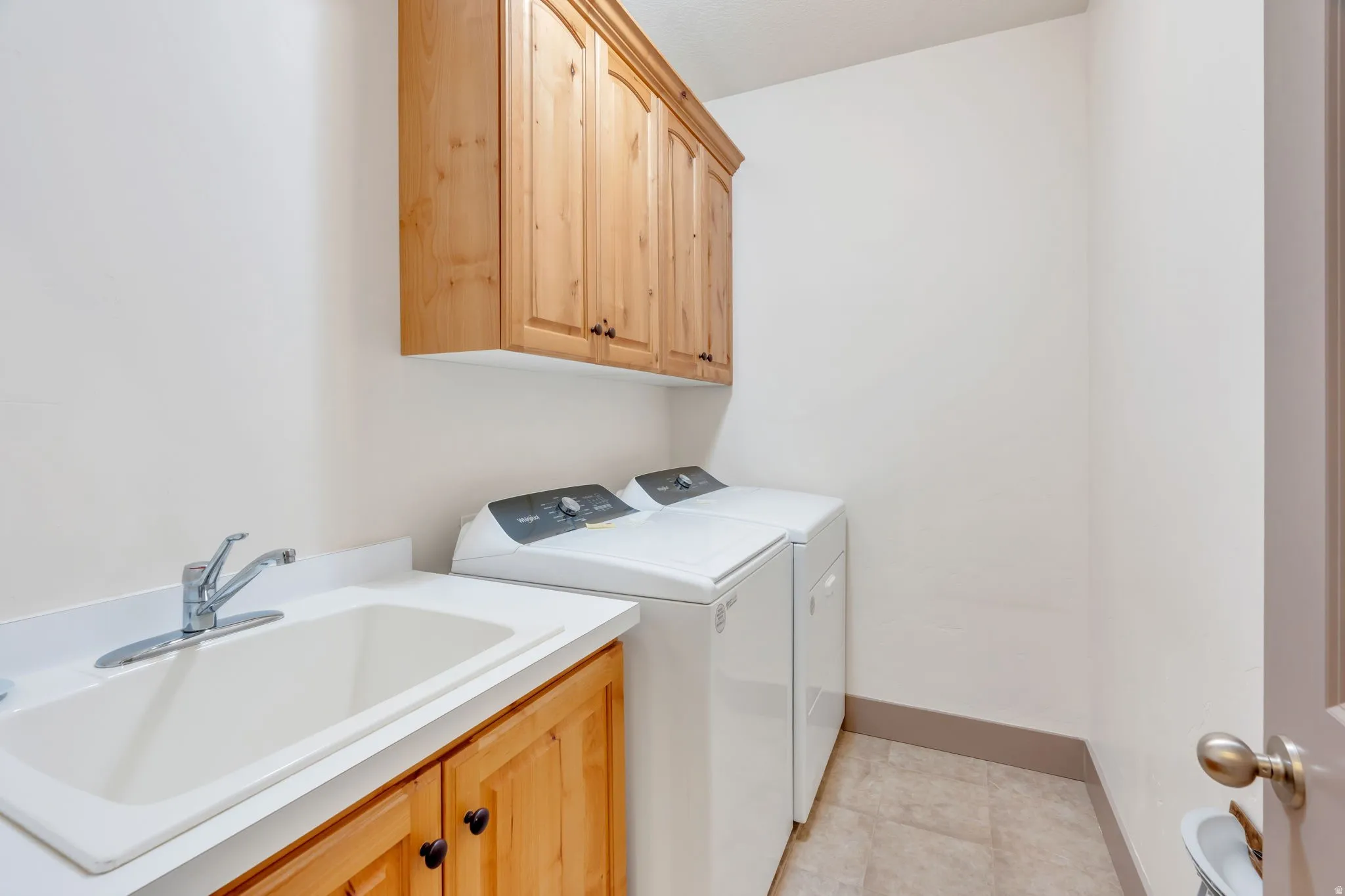 Utility room with a built-in sink, white countertop, and natural wood cabinetry