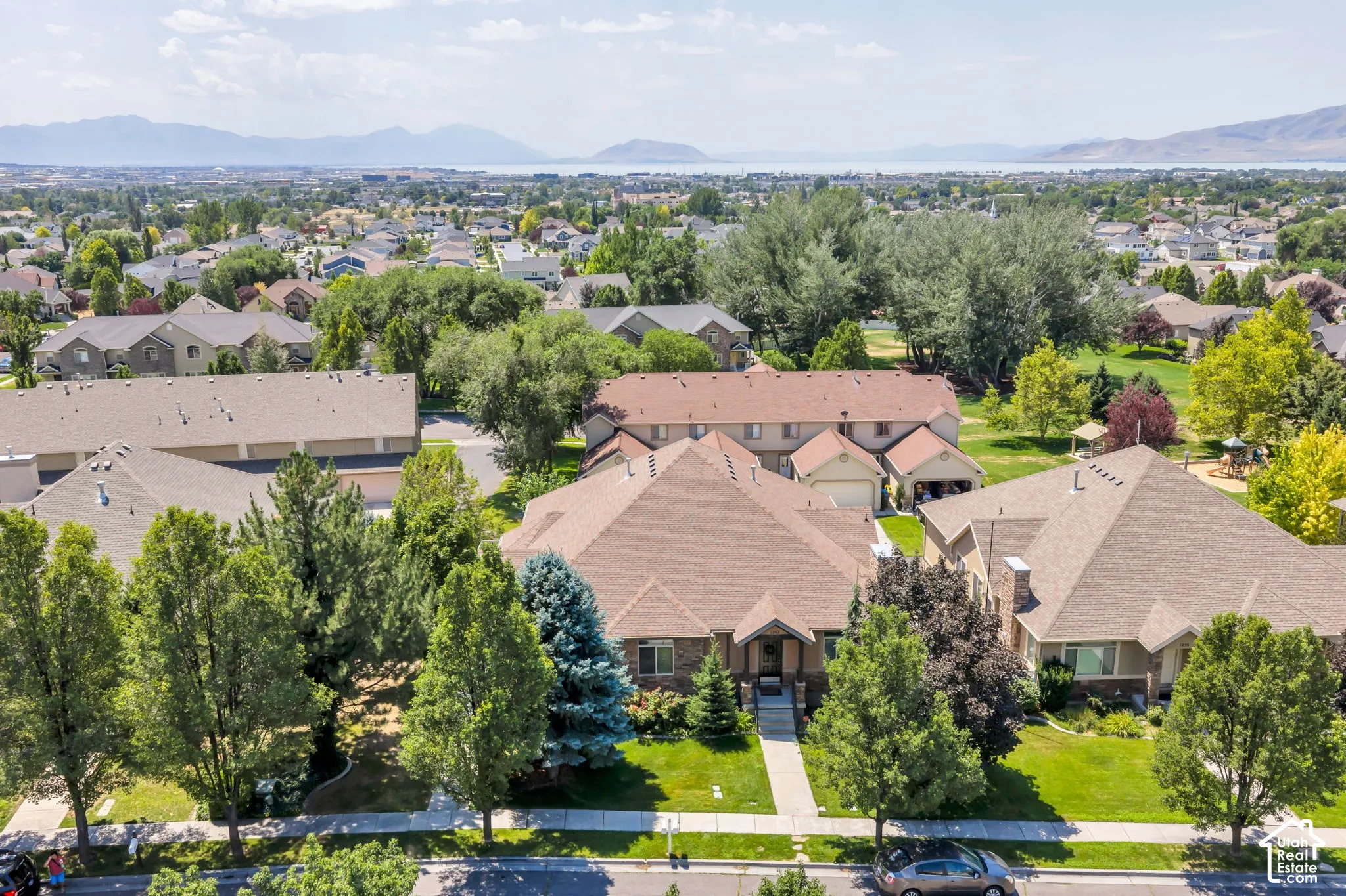 Ranch-style residence featuring a brick facade, mature trees, and a concrete pathway leading to the front entry