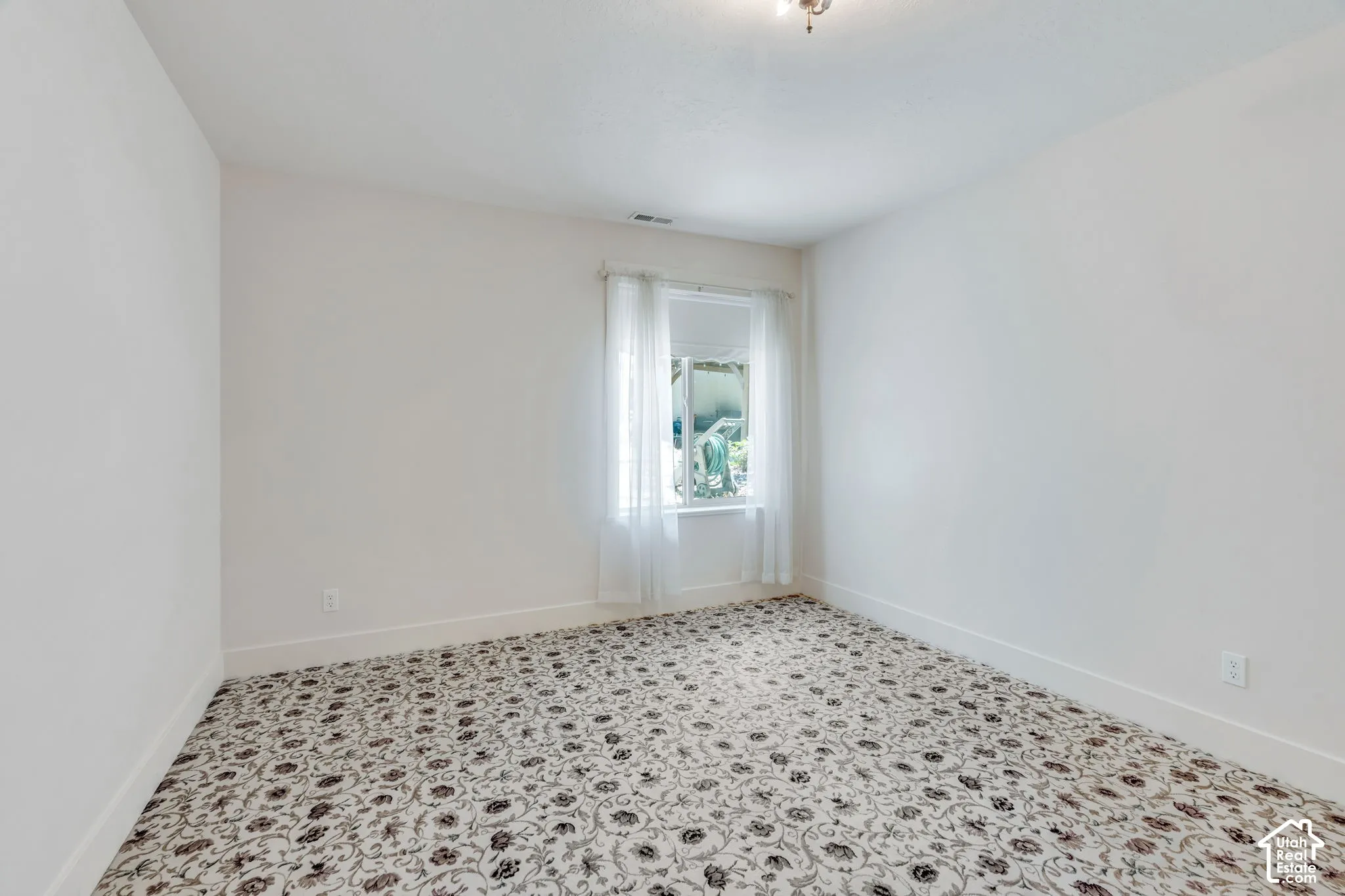 Room featuring patterned carpet flooring, white painted walls, and white baseboards
