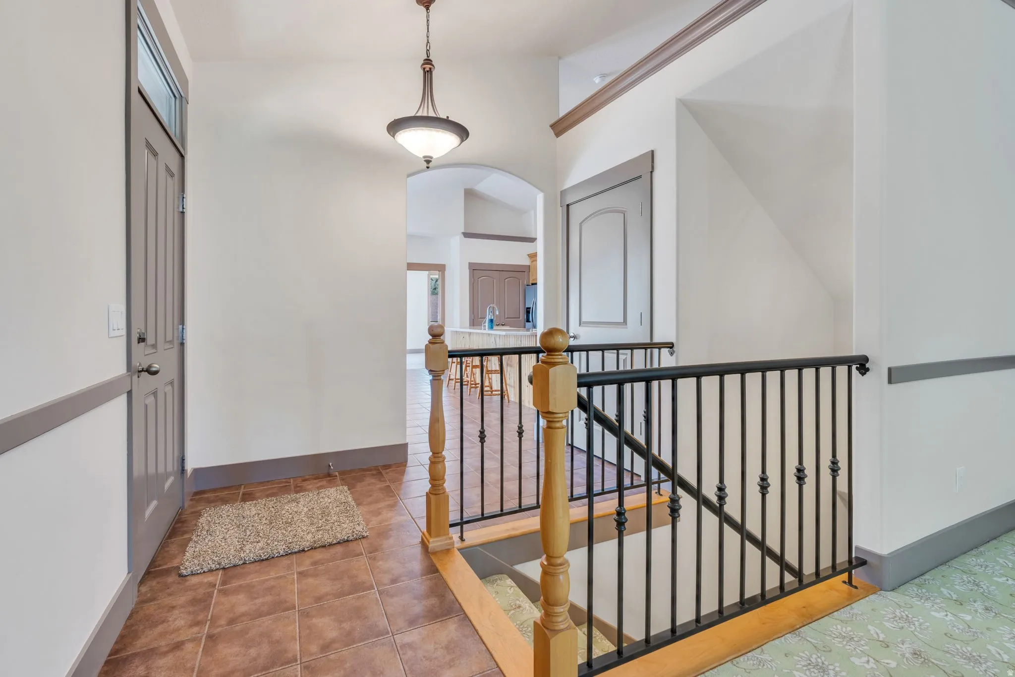 Entryway featuring tile flooring, a gray paneled door with transom window, and a decorative pendant light fixture