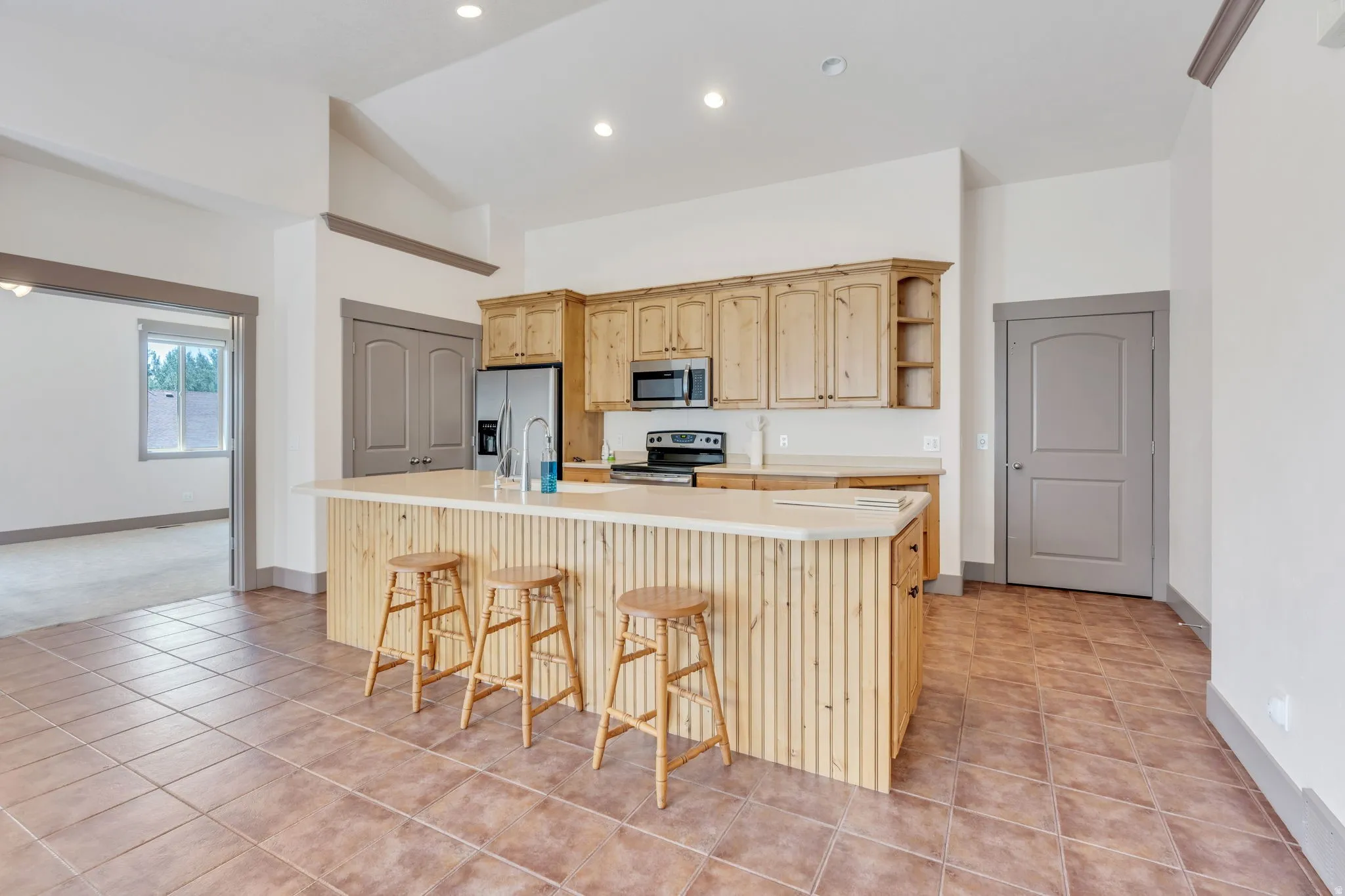 Kitchen featuring a central island with paneling, light-toned cabinetry, stainless steel appliances, and recessed lighting