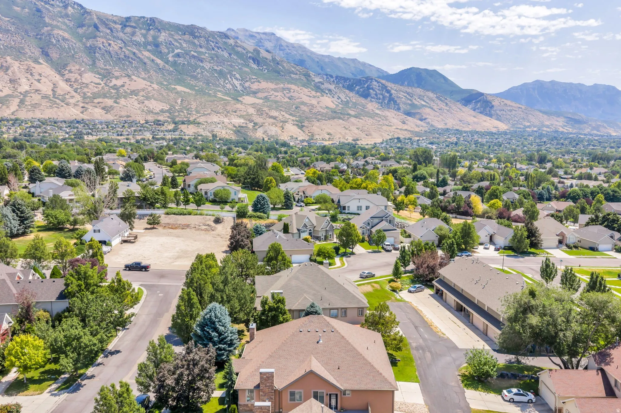 Residential neighborhood with varied home styles and mature trees, set against a backdrop of natural mountain terrain