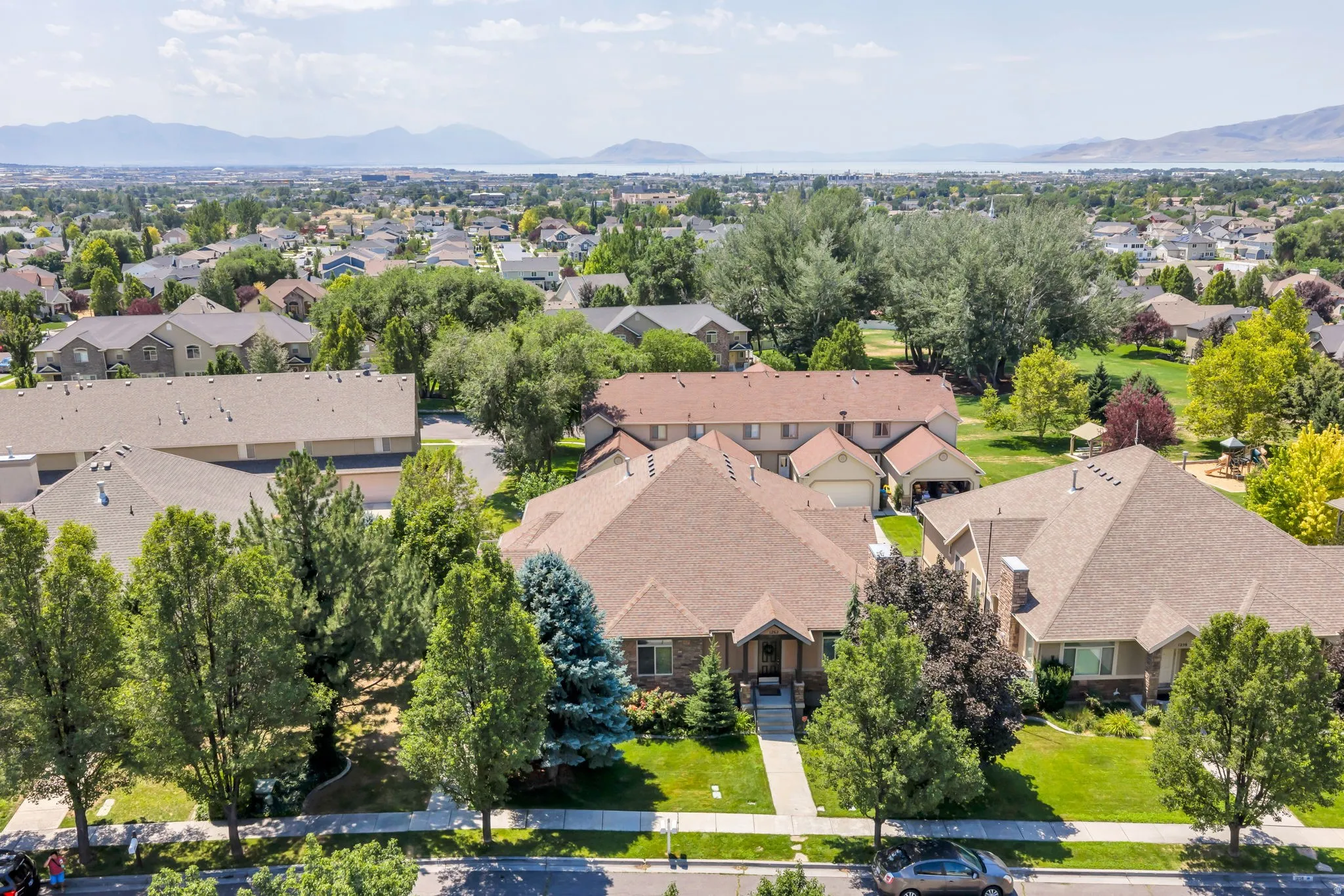 Ranch-style residence featuring a brick facade, mature trees, and a concrete pathway leading to the front entry