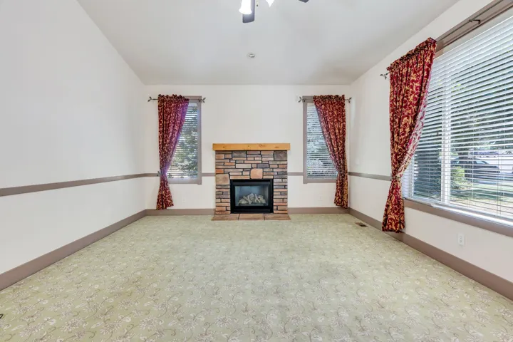 Central stone-faced fireplace with a wood mantle, complemented by light-toned wall finishes and a patterned floor covering