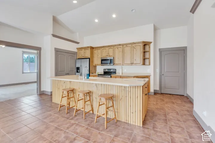 Kitchen featuring a central island with paneling, light-toned cabinetry, stainless steel appliances, and recessed lighting