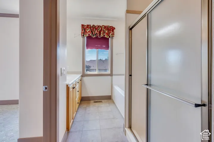 Bathroom featuring a shower enclosure with sliding door, a built-in bathtub, and a window with a valance