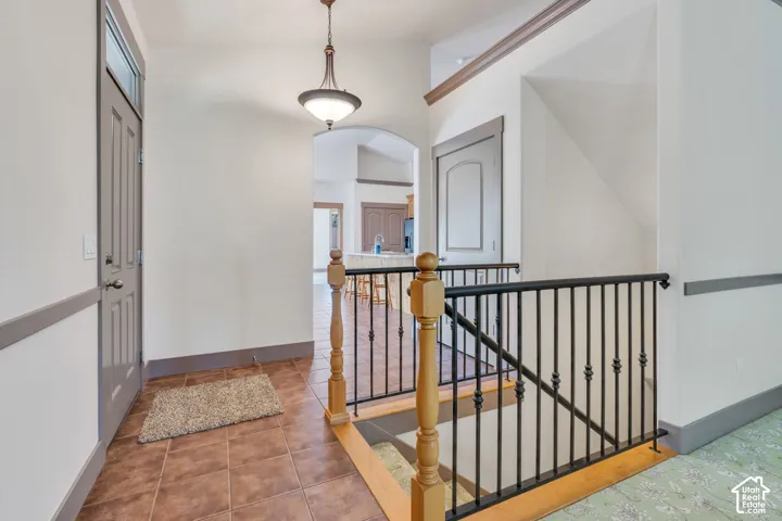 Entryway featuring tile flooring, a gray paneled door with transom window, and a decorative pendant light fixture