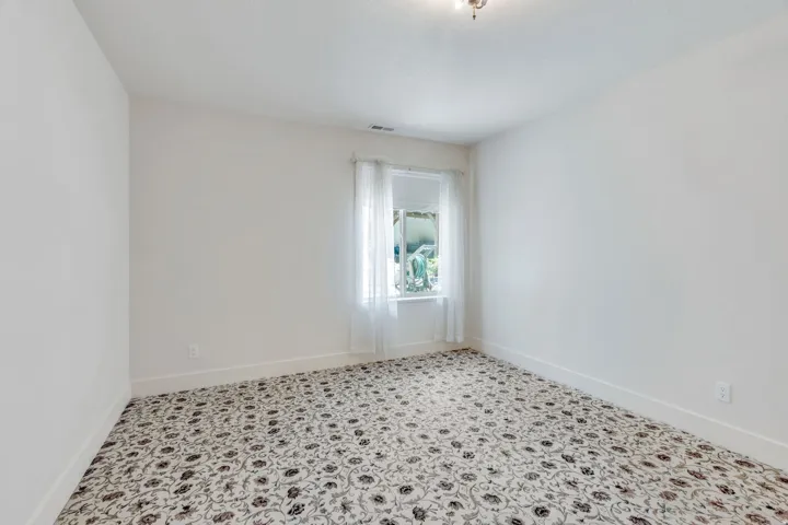 Room featuring patterned carpet flooring, white painted walls, and white baseboards