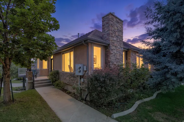 Exterior featuring a stone chimney, stucco siding, and stone base