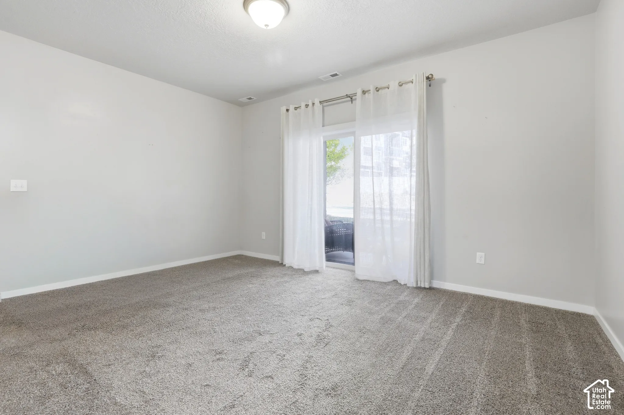 Neutral-toned interior space featuring wall-to-wall carpeting and sliding glass doors