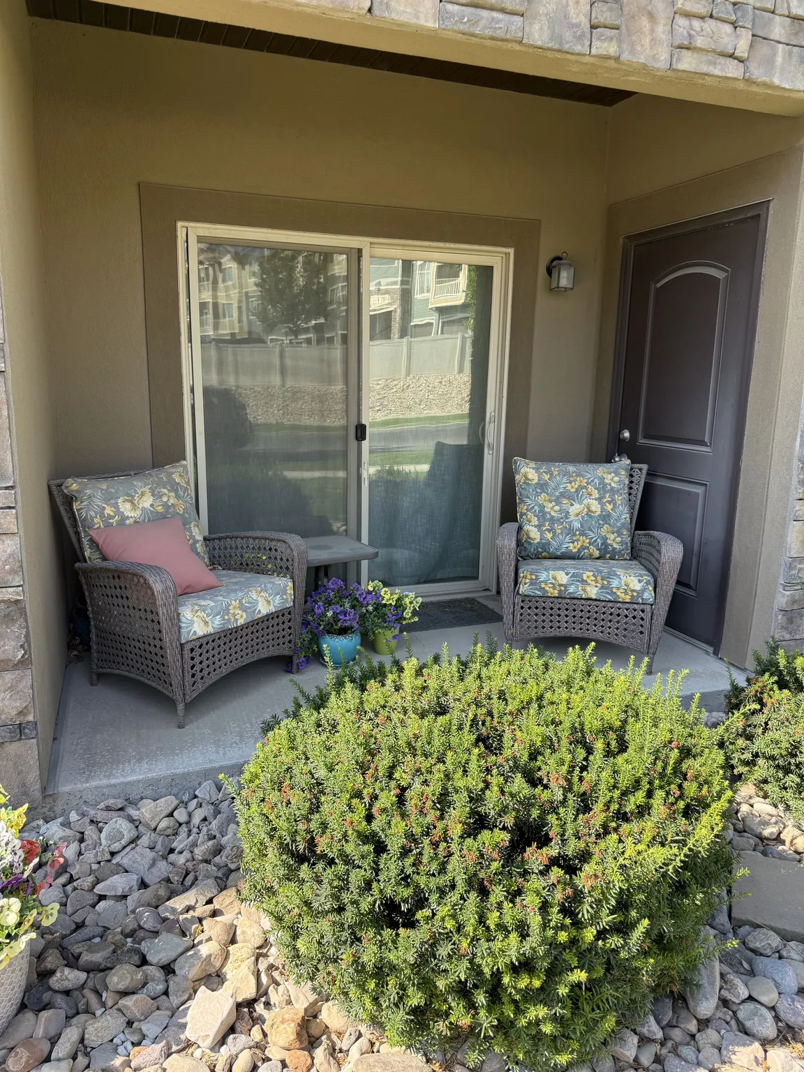 Covered patio featuring stucco siding and stone detailing