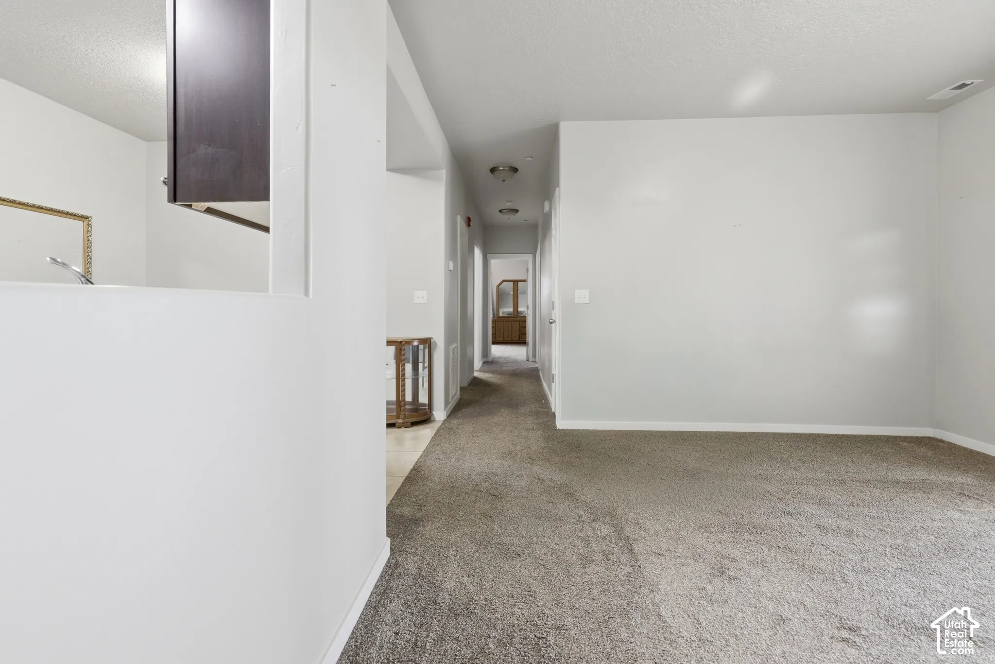Interior space featuring neutral-toned carpeting, wall-cutout window, and flush-mount ceiling lighting