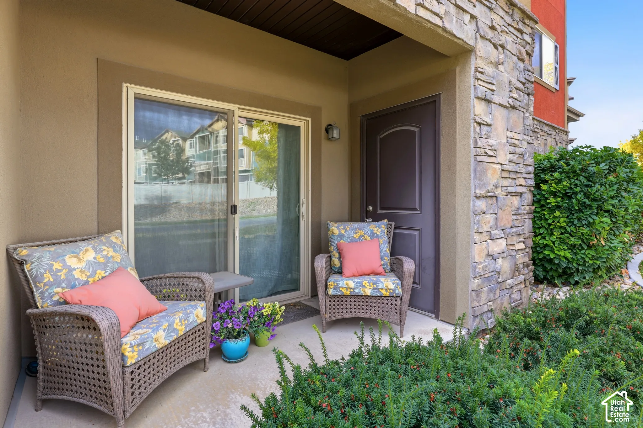 Covered patio featuring concrete flooring, stone veneer siding, and sliding glass entry door