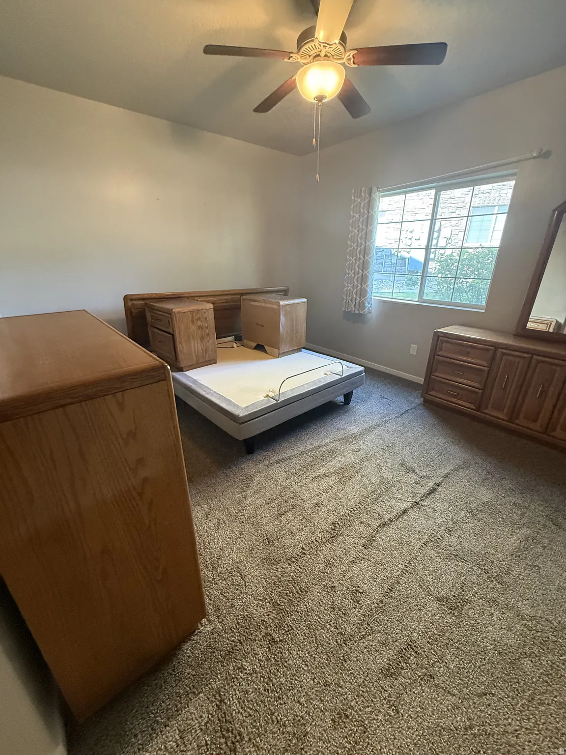 Carpeted room featuring a ceiling fan with light fixture, a window with horizontal blinds, and neutral wall tones