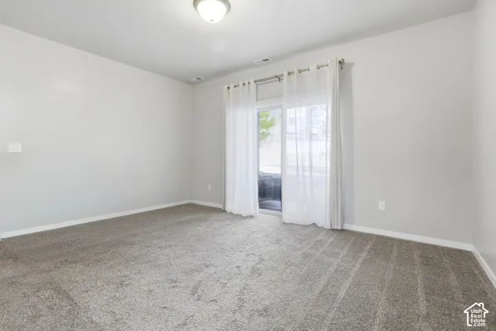 Neutral-toned interior space featuring wall-to-wall carpeting and sliding glass doors