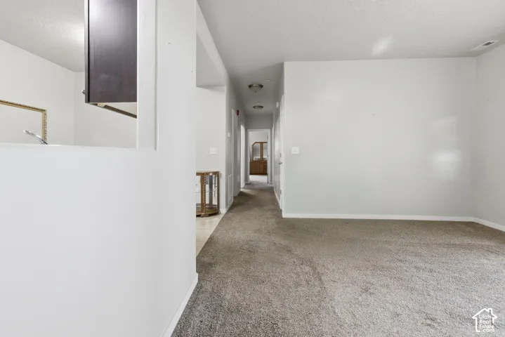 Interior space featuring neutral-toned carpeting, wall-cutout window, and flush-mount ceiling lighting