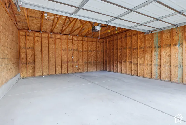 Attached garage featuring exposed timber framing, concrete flooring, and an automated overhead door opener