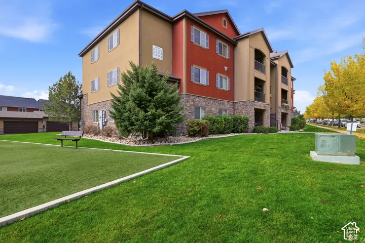 Multi-story exterior featuring stone veneer siding, stucco finish, recessed balconies, and manicured landscaping