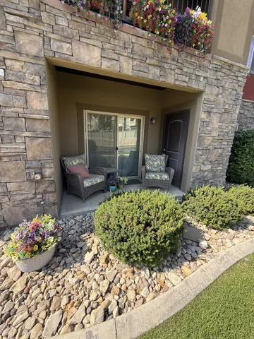 Stone veneer exterior with a recessed patio featuring a sliding glass door and an arched entry door