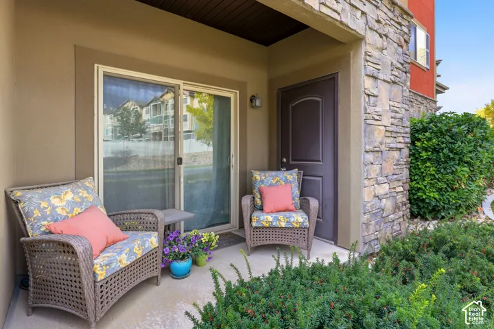 Covered patio featuring concrete flooring, stone veneer siding, and sliding glass entry door