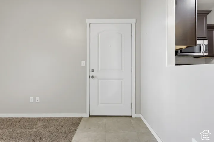 Entry featuring a white raised-panel door, neutral-toned wall paint, ceramic tile flooring, and carpeted flooring